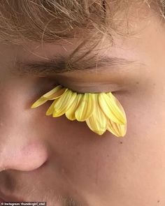 a close up of a person's face with a yellow flower on their forehead