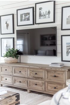 a living room with pictures on the wall and a large flat screen tv mounted above it