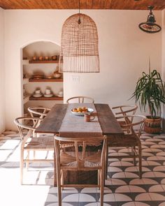 a dining room table and chairs in front of a potted plant on a tiled floor