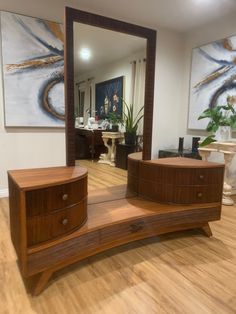 a large mirror sitting on top of a wooden dresser next to a plant in a living room