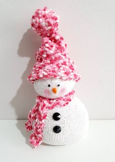 a knitted snowman with a pink hat and scarf on it's head