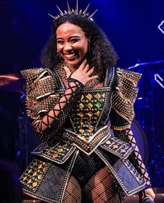 a woman in a costume on stage with her hands over her face and smiling at the camera