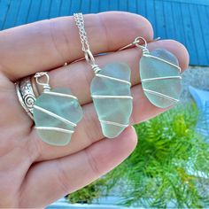 two sea glass necklaces are being held in someone's hand