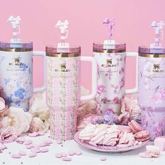 three coffee mugs sitting on top of a table next to cookies and marshmallows