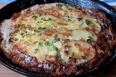 an omelet is sitting in a cast iron skillet on a wooden table