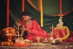 a woman sitting on the ground in front of a table with food and decorations around her