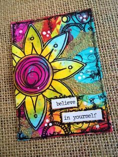 an art journal with words written on it and a sunflower in the middle, sitting on a burlap surface