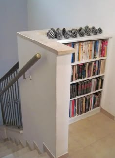 a bookshelf filled with lots of books next to a stair case