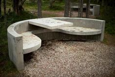 a concrete bench sitting in the middle of a forest