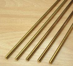 four brass colored straws on a wooden surface