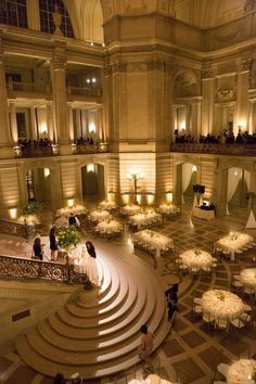 a large room filled with tables and white clothed tables next to each other in front of tall ceilings