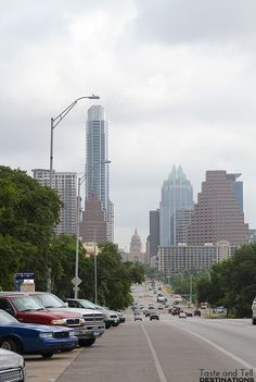 cars are parked on the side of an empty street in front of tall buildings and skyscrapers