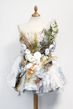 a dress made out of fabric and flowers on a mannequin headdress