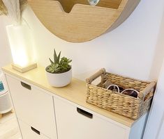 a white cabinet with two baskets on it and a mirror in the corner behind it