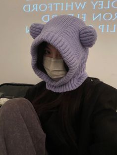 a woman wearing a face mask with a bear shaped knitted hat on her head