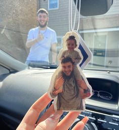 a person holding up a car keychain with an image of a man and woman on it