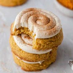 three pumpkin spice cookies stacked on top of each other with cinnamon rolls in the background