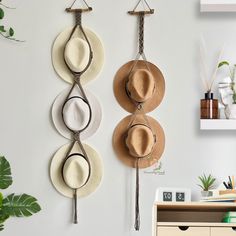 three hats are hanging on the wall next to each other, with hooks holding them