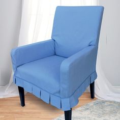 a blue chair sitting on top of a hard wood floor next to a white curtain