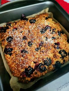 a square cake with blueberries and powdered sugar on top in a metal pan