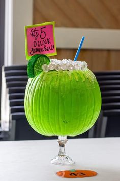 a green drink sitting on top of a table next to a sign that says 5 o'clock somewhere