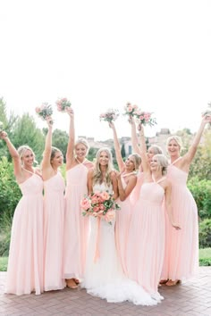 a group of bridesmaids in pink dresses holding bouquets and posing for the camera