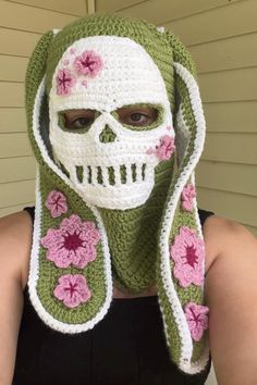 a woman wearing a crocheted skull mask with flowers on it