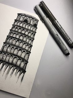 a drawing of the leaning tower of pisa with two markers next to it on a table