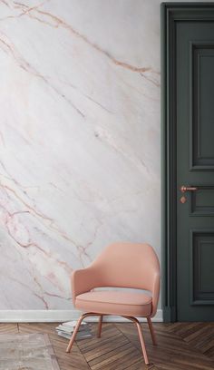 a pink chair sitting on top of a wooden floor next to a wall with white marble