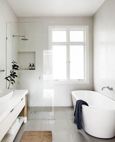 a bathroom with a large white bathtub sitting next to a sink and a window