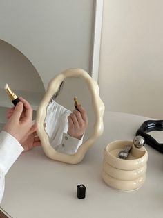 a person holding a pen and writing on a piece of paper in front of a mirror