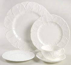 white dinnerware set with leaf design on the rims and saucers, all in different shapes and sizes