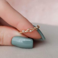 a woman's hand with a gold ring on it and a green manicure