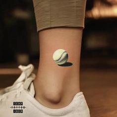 a woman's foot with a tennis ball tattoo on her left side ribcage