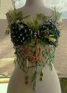 a mannequin is adorned with beads and plants in the shape of a bra