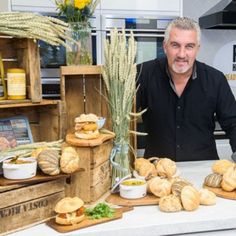 a man standing behind a counter filled with bread