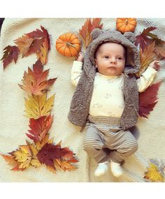 a baby laying on top of a blanket covered in leaves