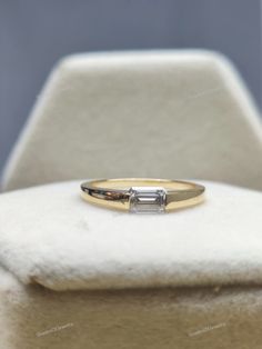 an engagement ring with a baguette cut diamond sitting on top of a white chair