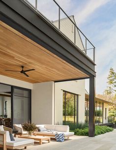 an outdoor living area with couches, tables and a ceiling fan on the roof