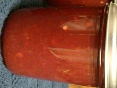 two jars with red liquid sitting next to each other on a blue towel in front of a metal container