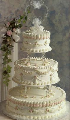 a three tiered wedding cake sitting on top of a table next to a bouquet