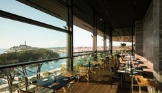 an outdoor restaurant with tables and chairs overlooks the cityscape from its large windows