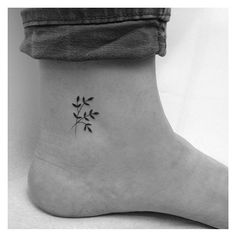 a black and white photo of a small tattoo on the ankle that has three leaves