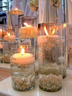 candles in glass vases filled with water and pearls