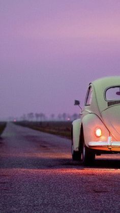 an old beetle driving down the road at dusk