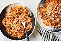 two pans filled with pasta and topped with parmesan cheese