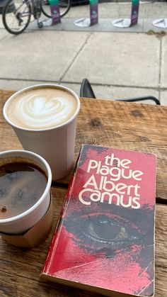 two cups of coffee and a book on a wooden table