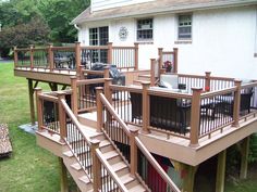 a deck with stairs leading up to the top floor and an outdoor dining area on the second level