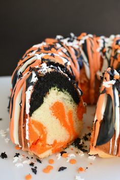 an orange and black cake with white frosting is cut in half to show the inside