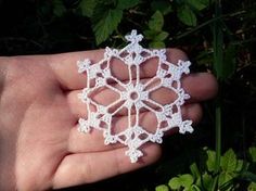 a hand holding a white crocheted snowflake